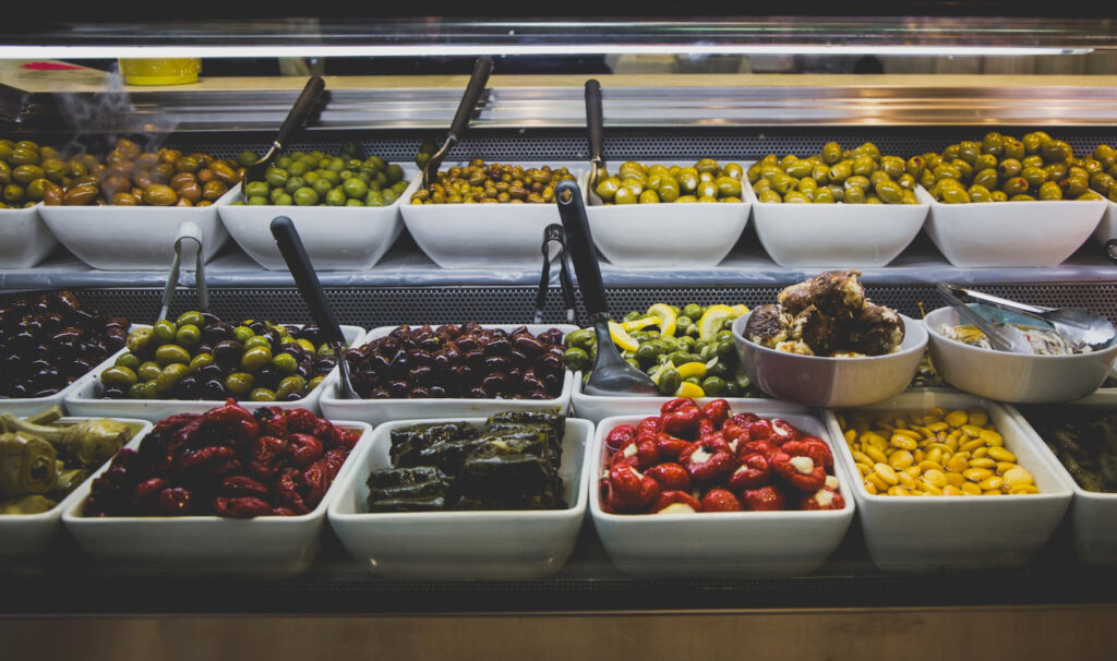 Étalage coloré d'olives et antipasti dans une épicerie.